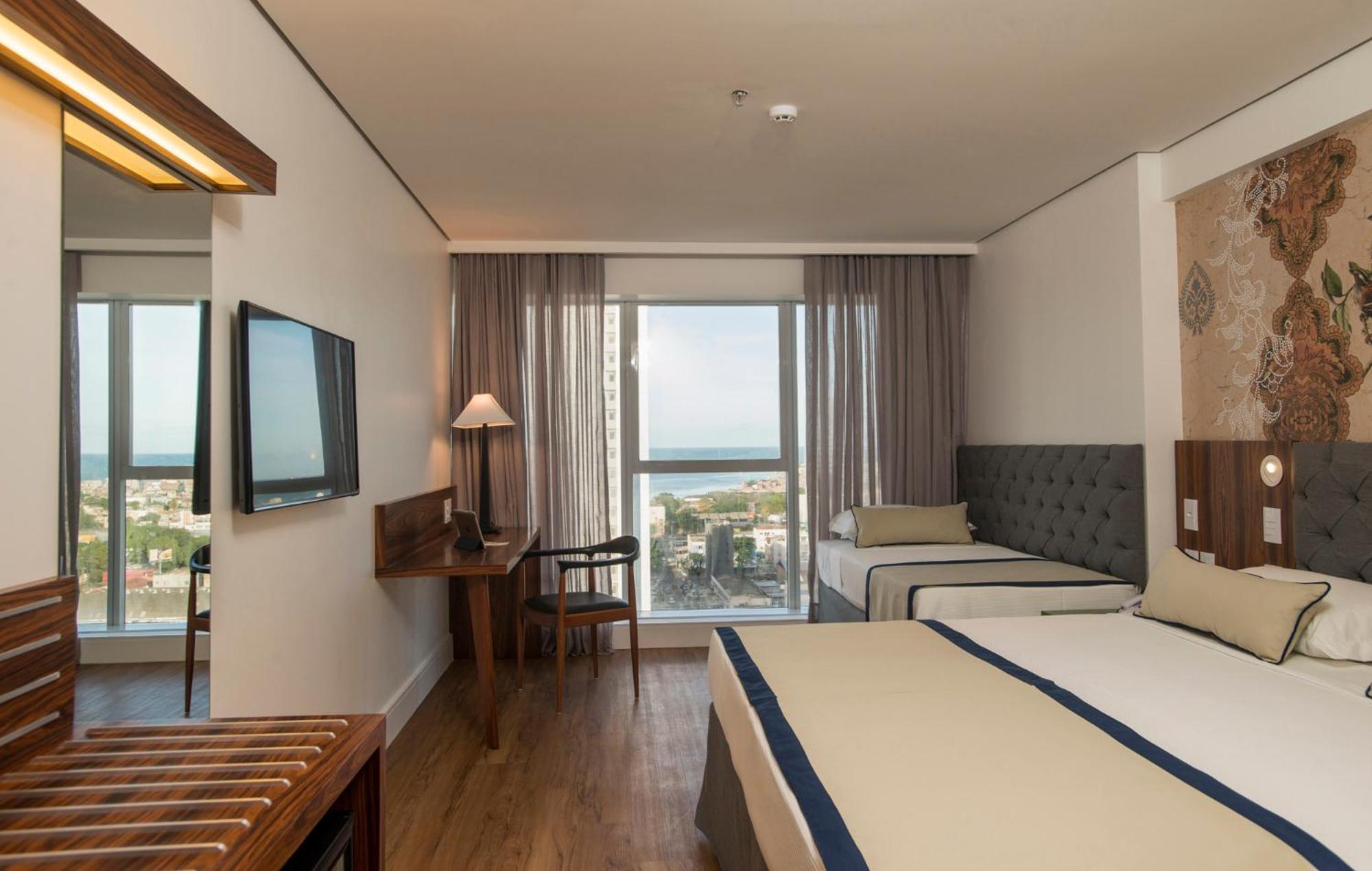 Hotel Luzeiros Recife Exteriör bild The photo shows a hotel room that features a modern and comfortable design. There are two beds: one larger bed and a smaller twin bed. The room has large windows with curtains that allow natural light to enter, offering a view of the outside, possibl